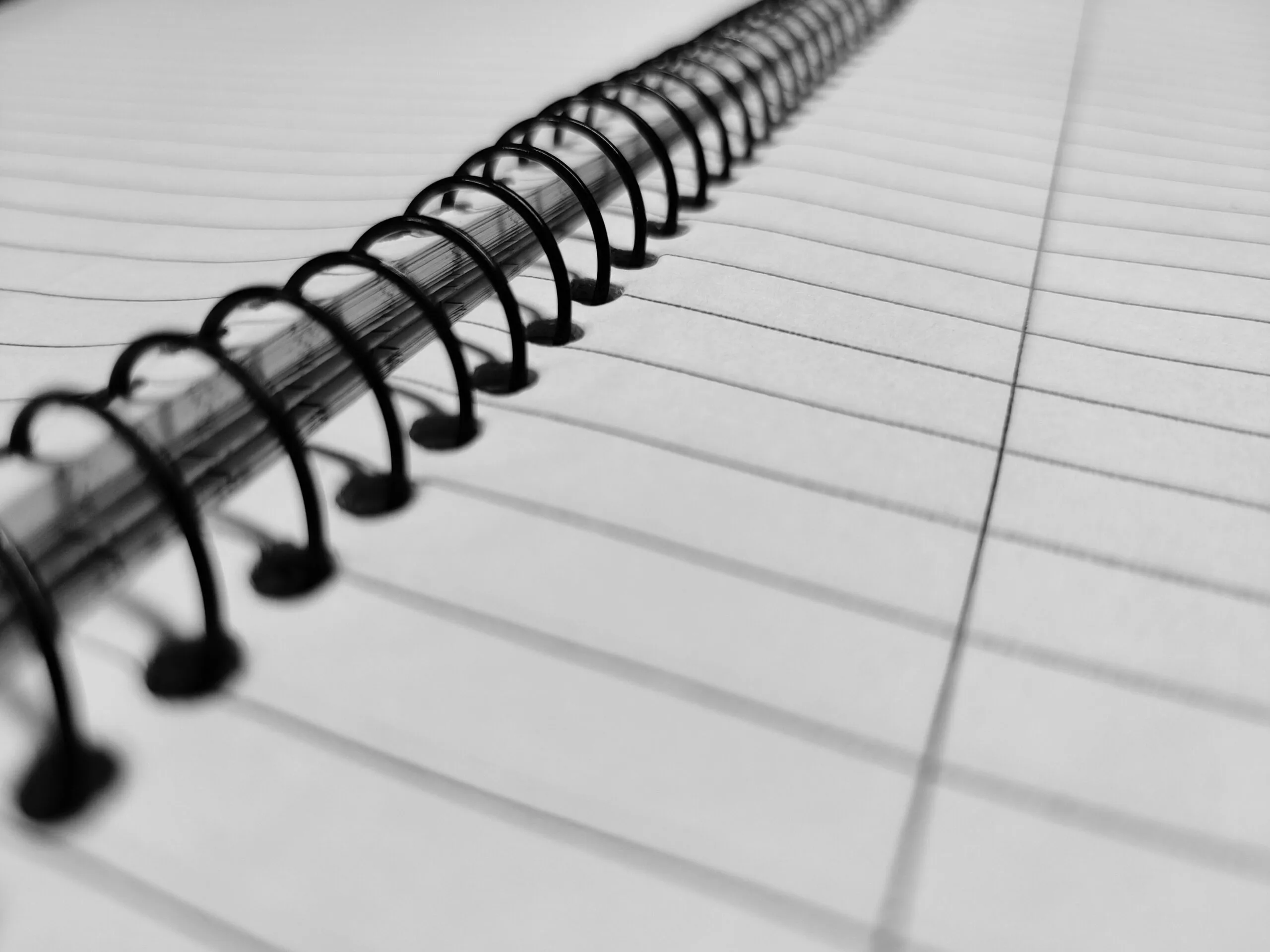 Detailed close-up of an open spiral notebook with lined pages and wire binding.