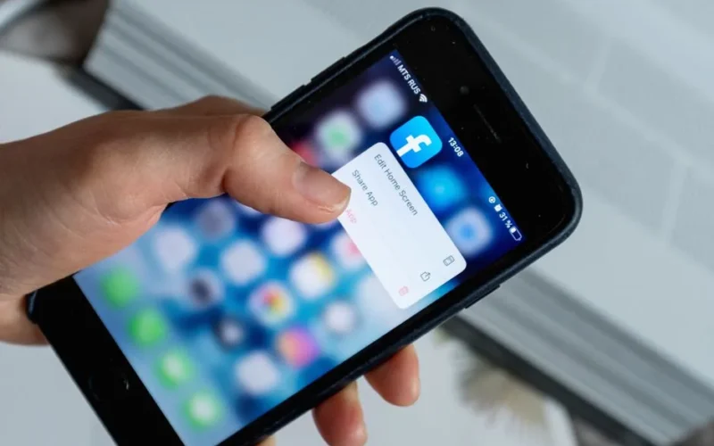 From above of crop anonymous person touching blurred cellphone screen while opening app and choosing option from pop up window