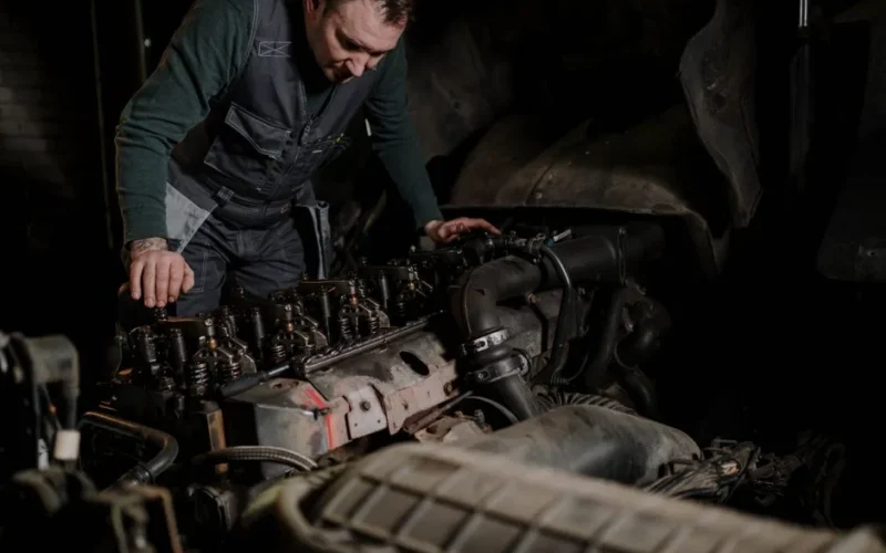 Mechanic focused on vehicle engine repair in an indoor workshop.