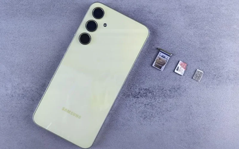 Yellow smartphone with SIM tray, memory card, and SIM card on gray background.