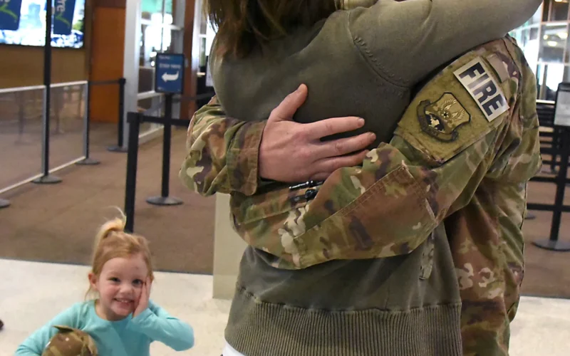 U.S. Air Force Senior Master Sgt. Travis Schauer, a fire fighter assigned to the 119th Civil Engineer Squadron, North Dakota Air National Guard, gets a welcome home hug from his wife, as his daughter looks on with astonishment upon his return home from a six-month deployment to southwest Asia at Hector International Airport, Fargo, N.D., Jan. 23, 2018. (U.S. Air National Guard photo by Senior Master Sgt. David H. Lipp)