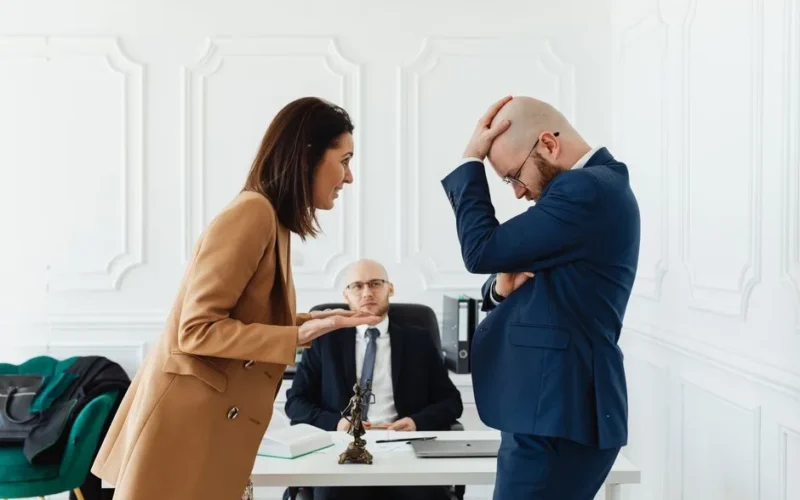A couple having a heated argument in a law office with their attorney observing.