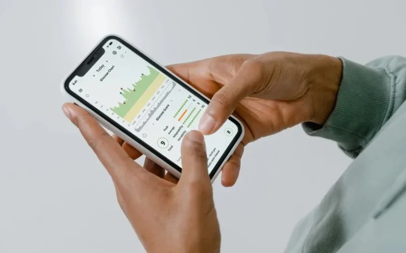 Close-up of hands holding a smartphone showing a health tracking app with charts and data.