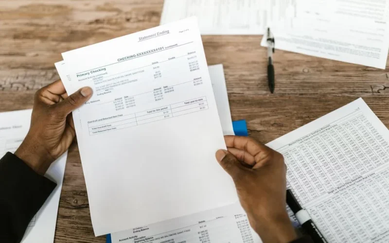 Hands holding financial papers for tax preparation and analysis.