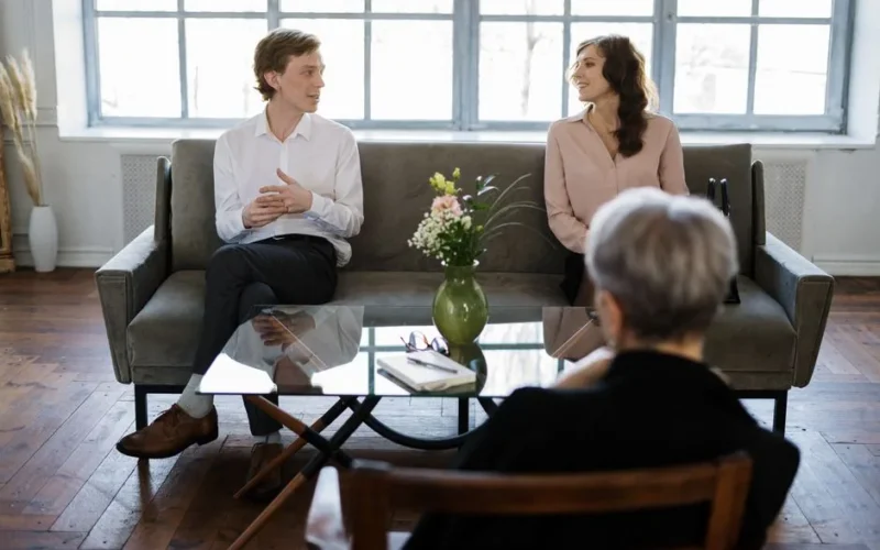 Couple engaged in a therapy session with a counselor in a loft setting.
