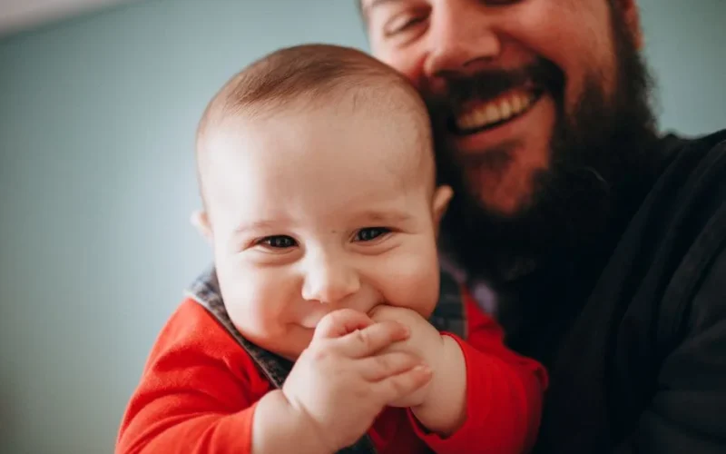 A heartwarming close-up of a smiling father holding his joyful baby.