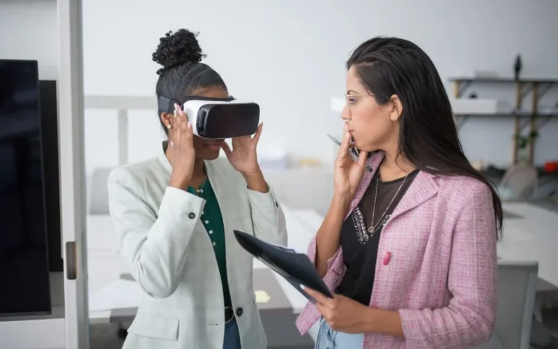 Two professional women collaborating using VR technology in a modern office setting, showcasing innovation.