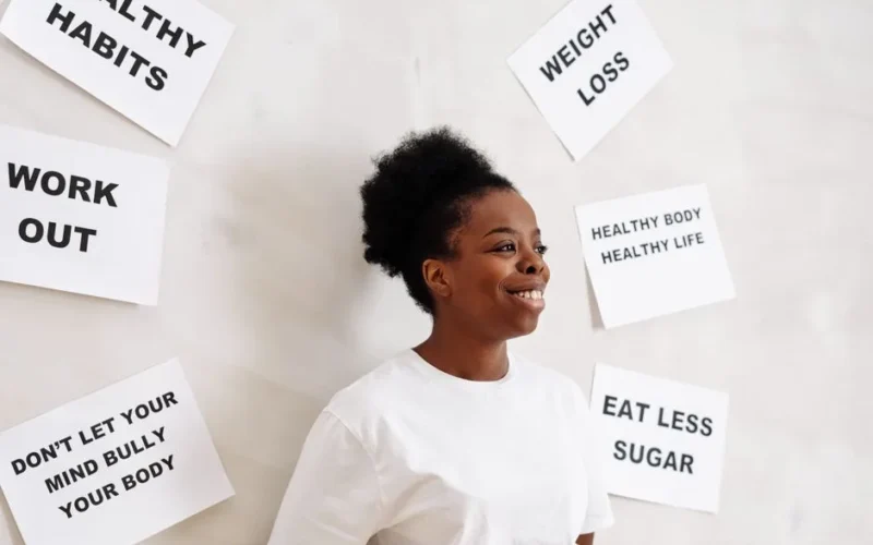 Portrait of a smiling woman surrounded by health motivation signs on a white background, promoting a healthy lifestyle.