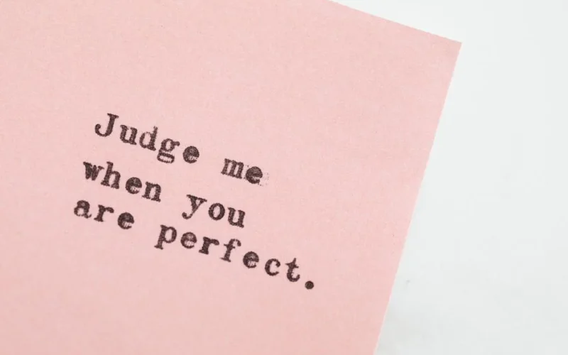 Close-up of an inspirational quote on pink paper, offering a message of judgment and perfection.
