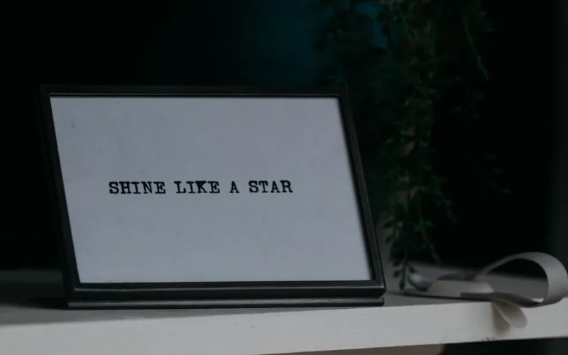 Motivational quote 'Shine Like a Star' in a black frame on a desk.
