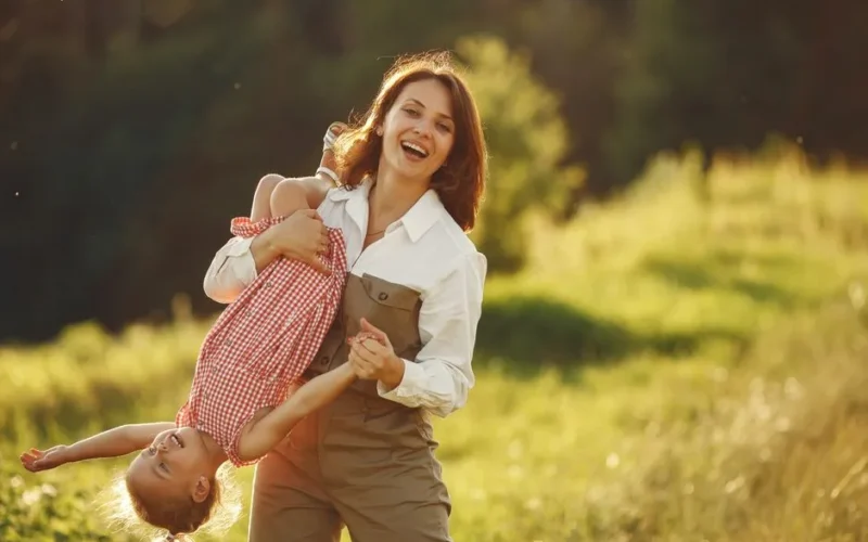 A mother playing with her daughter outdoors, enjoying a playful and joyful moment at sunset.