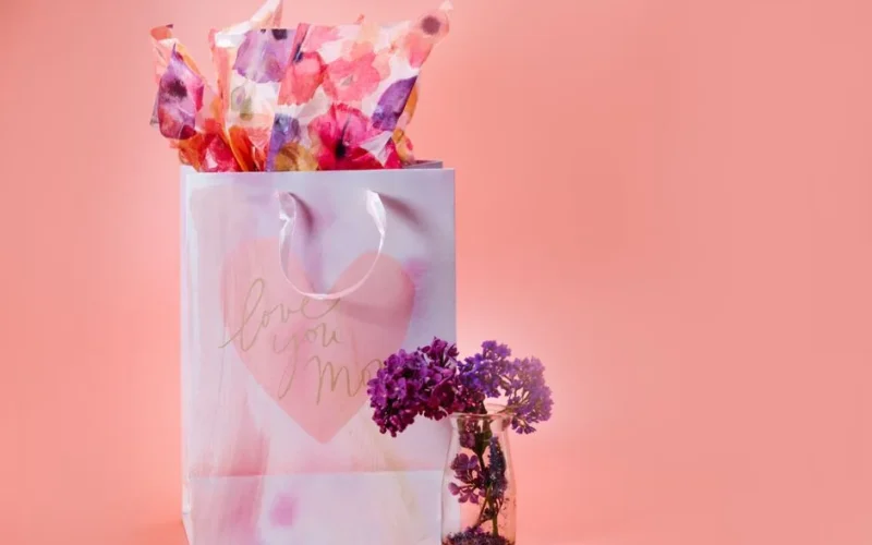 A charming Mother's Day gift bag with decorative flowers against a soft pink background.