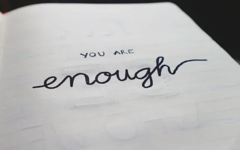 A close-up of a notebook page with motivational handwritten text: "You are enough."