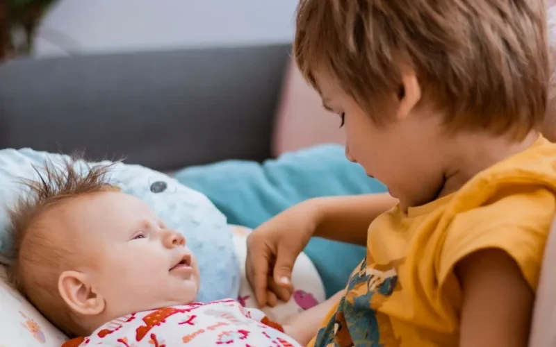 A heartwarming scene of a young boy with his baby sibling sharing a tranquil moment.