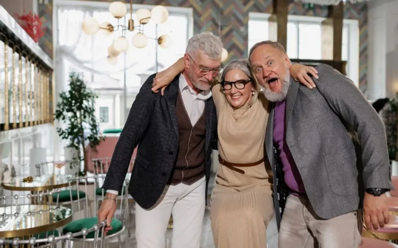 Elderly friends laughing and hugging at a lively indoor café setting, showcasing friendship.