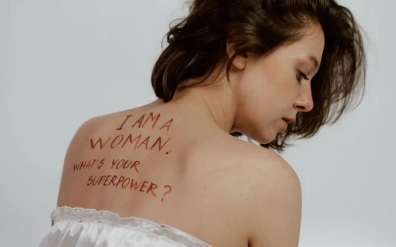 A woman with empowering feminist message written on her back in a studio setting.