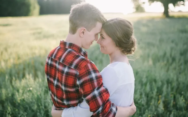 A loving couple embraces in a sunlit field, symbolizing romance and happiness.