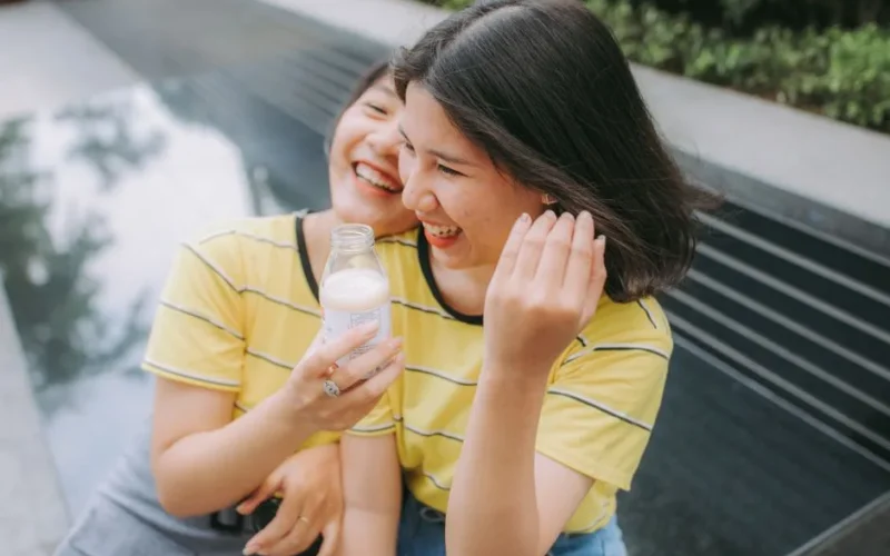 Two young women sharing a joyful moment outdoors, smiling and enjoying their time together.
