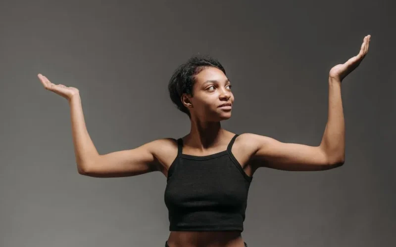 Portrait of a confident woman with raised arms in a studio setting, expressing positivity.