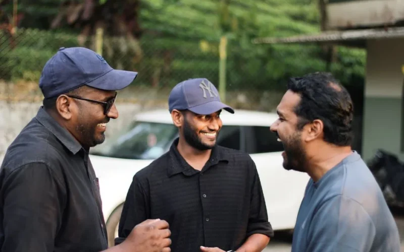Three men enjoy a shared moment of laughter outdoors, capturing camaraderie in natural light.