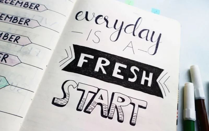 Notebook page featuring motivational quote 'Everyday is a fresh start' with colorful pens.