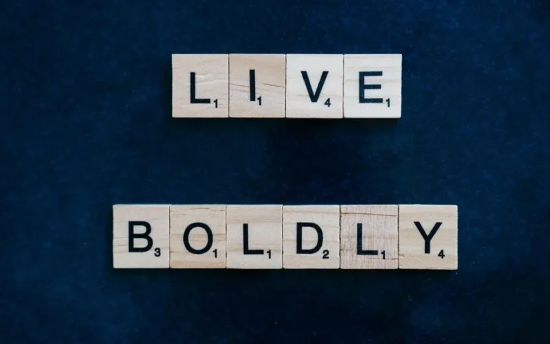 Scrabble tiles spelling 'Live Boldly' on a textured blue surface, conveying inspiration.