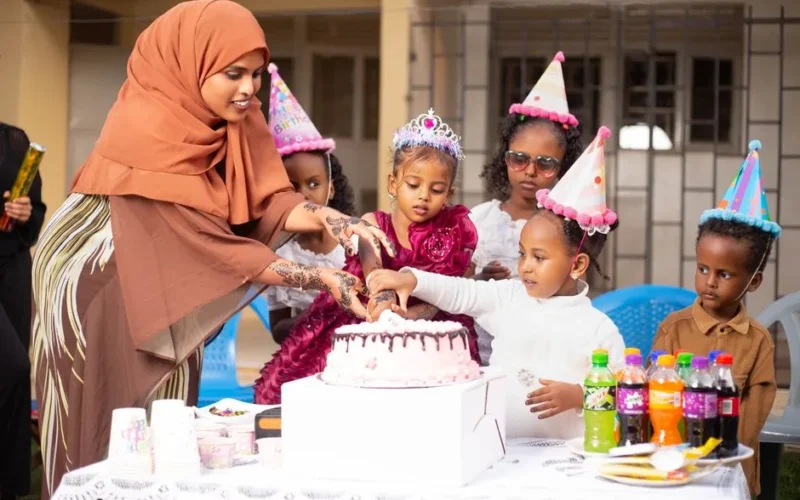 Children celebrating a birthday with cake and party hats, surrounded by friends and family.