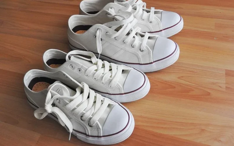 Pair of white sneakers on a clean wooden floor, casual and sporty look.