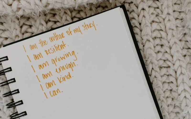 Notebook with handwritten affirmations on knitted fabric background.