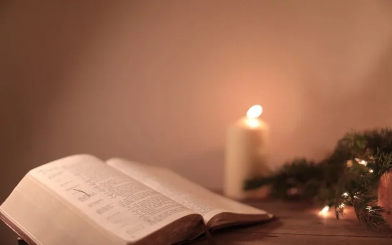 Open Bible with candle and festive greenery creates a serene ambiance.