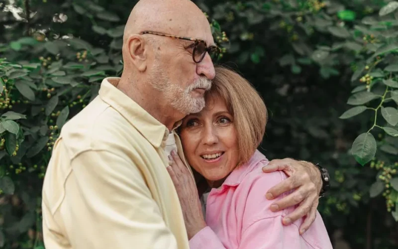 An affectionate elderly couple in an outdoor setting showing love and connection.