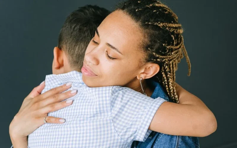 A loving mother holding and comforting her son in an emotional embrace indoors.