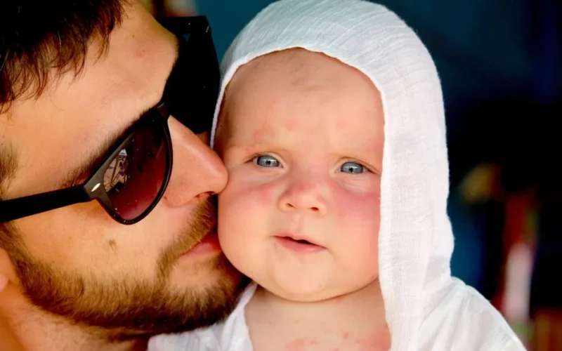 Heartwarming close-up of a father embracing his baby dressed in white.