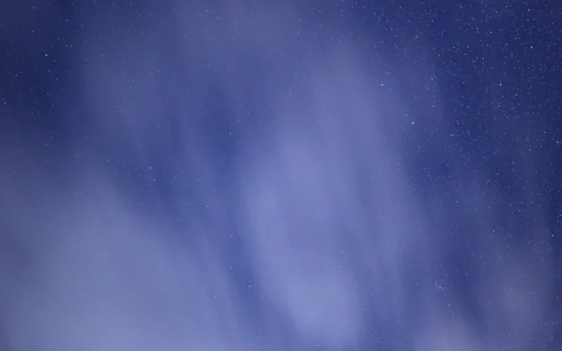 Peaceful night sky featuring scattered stars partly obscured by wispy clouds.