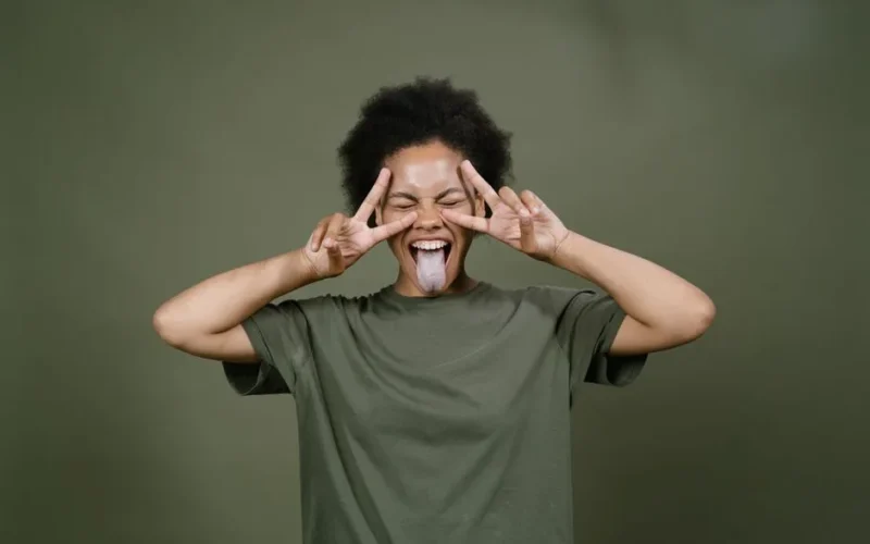Energetic woman with afro hair joyfully posing with playful expressions and peace signs.