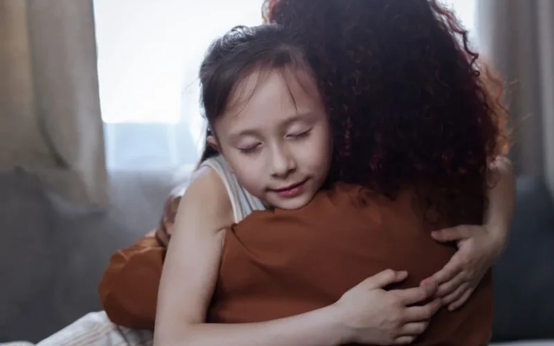 A heartfelt mother-daughter hug indoors, symbolizing love and connection.