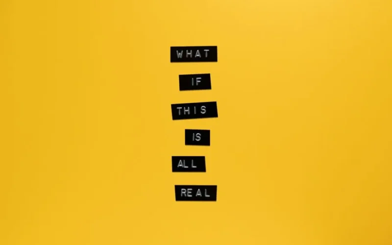 Inspirational text 'What if this is all real' on yellow surface.