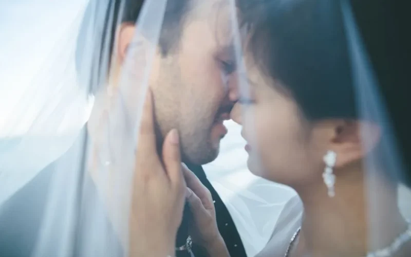 Intimate close-up of a bride and groom kissing under a veil, capturing their love and special moment.