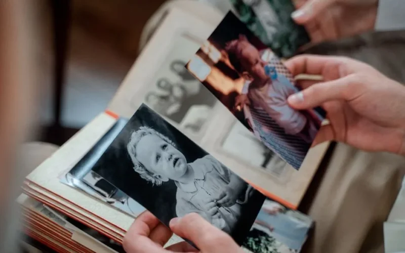 Close-up of hands examining nostalgic family photos in an album.