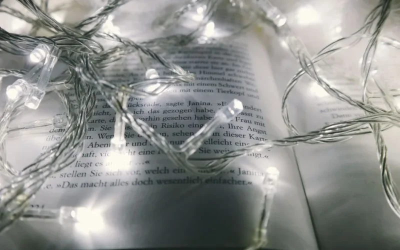 Warm glowing string lights artfully arranged over an open book, creating a cozy and festive atmosphere.