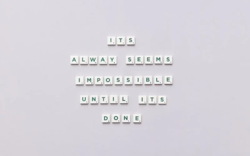 Motivational quote 'It always seems impossible until it's done' in Scrabble tiles.