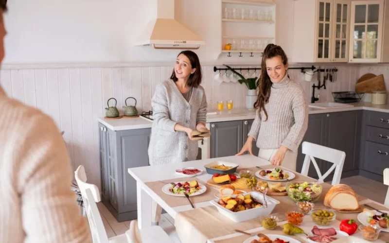 Two women enjoying a cozy breakfast in a bright kitchen filled with delicious food.