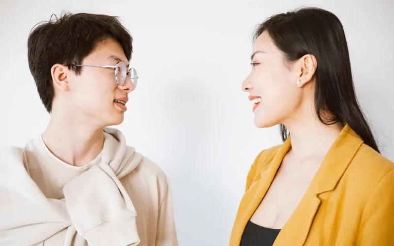 Smiling man and woman having a friendly conversation in a bright indoor setting.
