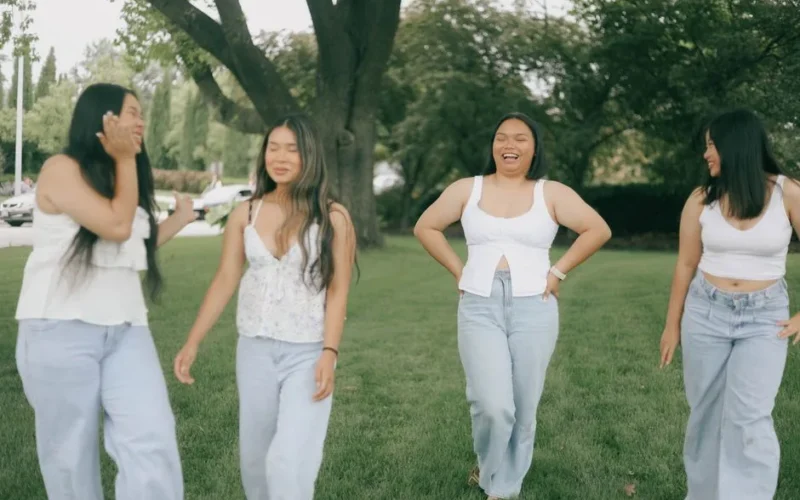 Four friends laughing and enjoying a sunny day in a park.