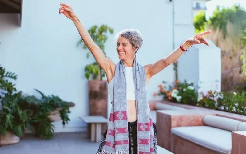 Elderly woman joyfully dancing with arms raised outdoors, embodying happiness and positive aging.