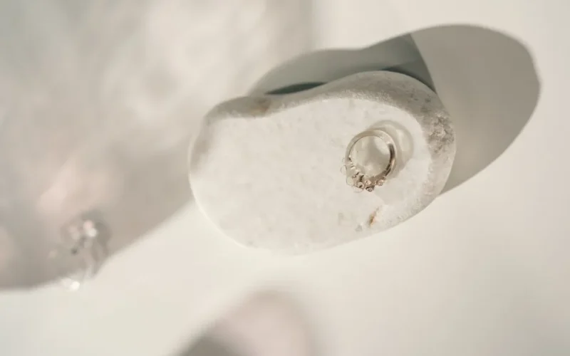 Minimalist silver ring displayed on a smooth white stone with soft lighting, perfect for jewelry showcases.