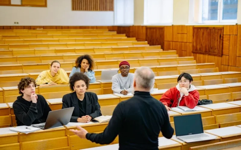 Professor teaching a diverse group of students in a university lecture hall.