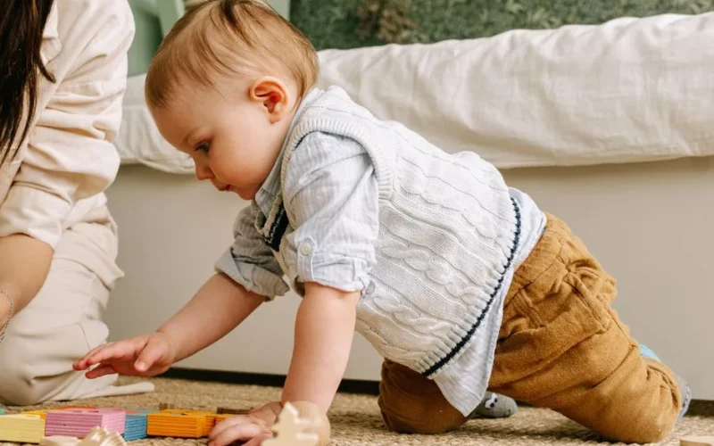 Charming scene of a joyful baby boy engaging with colorful wooden blocks on the floor.