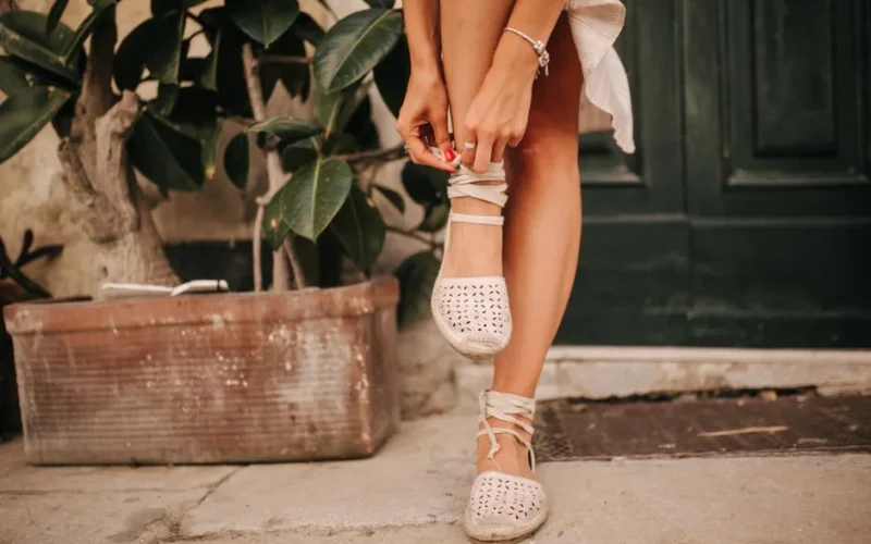 Close-up of a woman tying espadrille shoes on a warm day.
