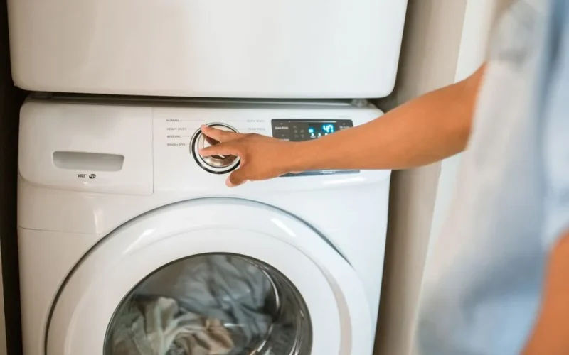 Close-up of a person adjusting a washing machine in a modern laundry room.